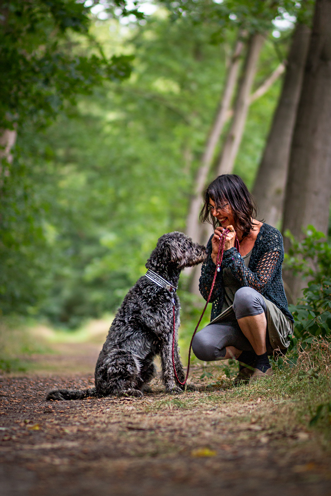 Frau kniet vor einem Hund im Wald